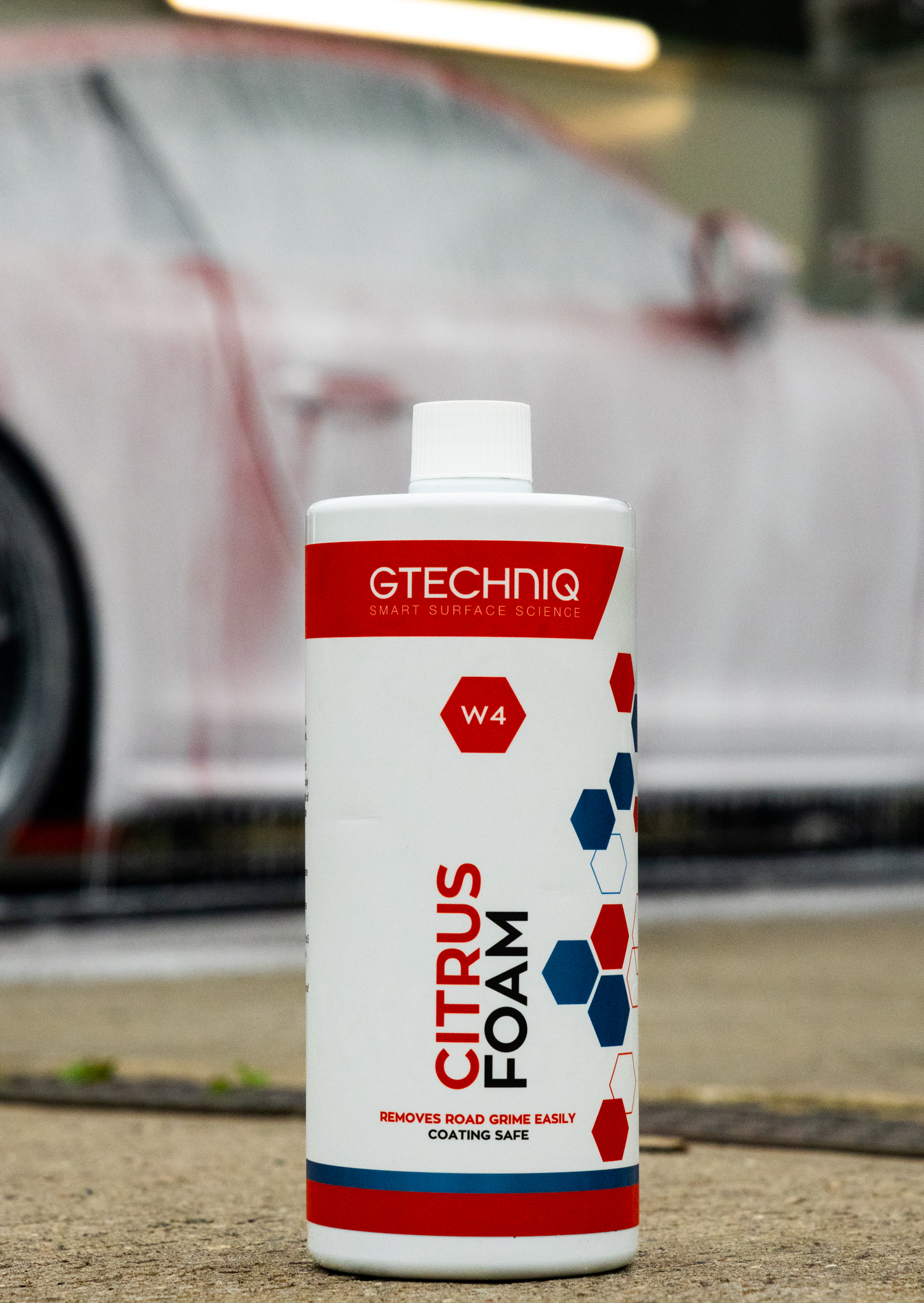 Pressure washer rinsing snow foam from a black coated supercar
