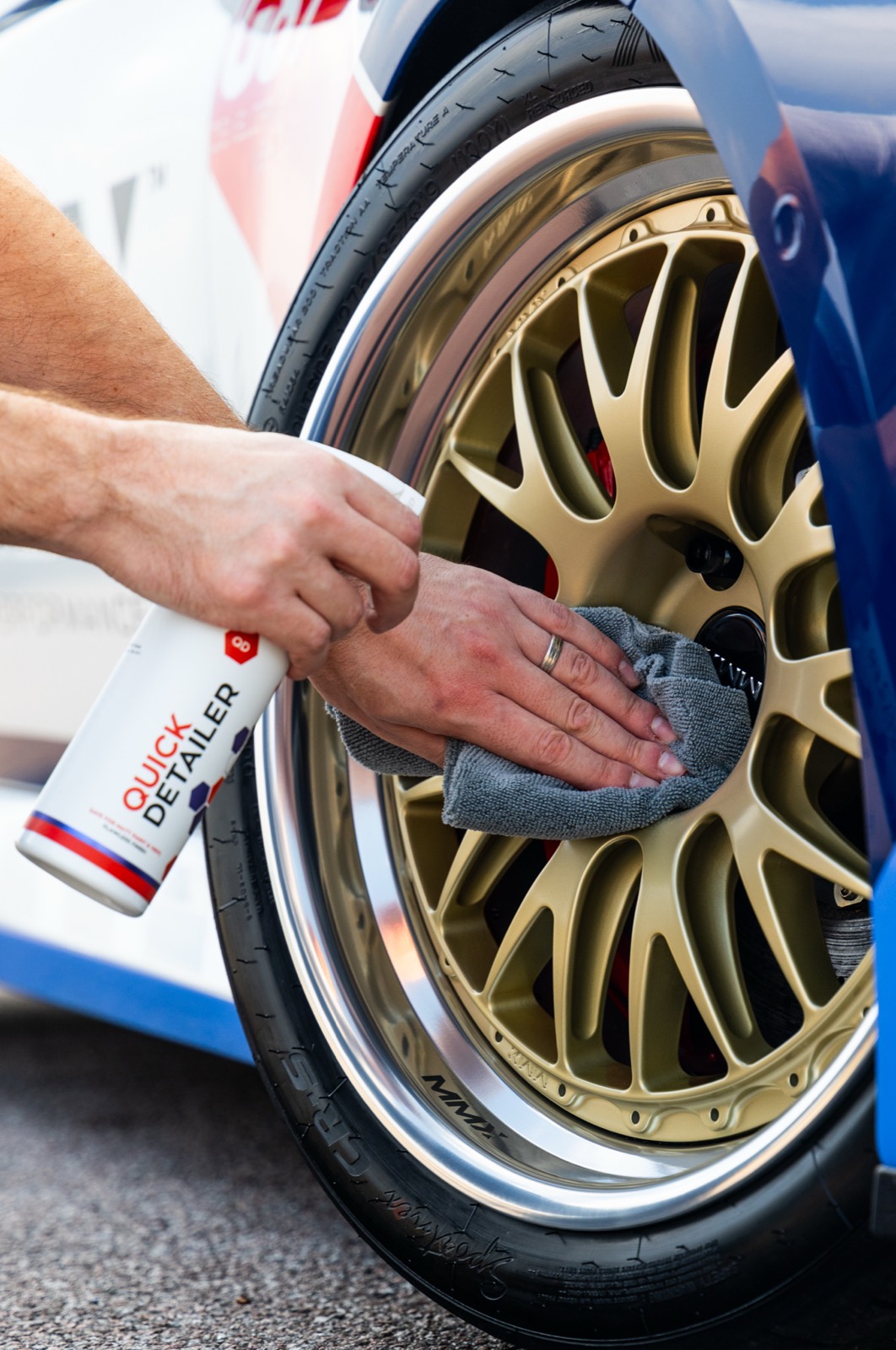 Gtechniq Quick Detailer being used with a microfibre to refresh the wheel and paintwork of a racing BMW